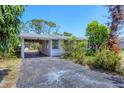 A one-story home with a carport and mature trees at 2128 Pennsylvania Ave, Englewood, FL 34224