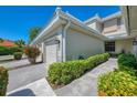 Side view of a two-story townhouse, showcasing well-kept landscaping, neutral exterior, and an attached two-car garage at 3433 Grand Vista Ct # 102, Port Charlotte, FL 33953
