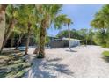 A beautifully landscaped backyard featuring lush palms and a screened-in pool area at 4065 N Beach Rd # A, Englewood, FL 34223