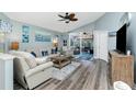 Inviting living room with wood flooring, neutral furniture, blue accents, and sliding glass doors to a screened porch at 4207 Fairway Pl, North Port, FL 34287