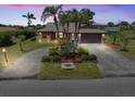 Charming home featuring lush landscaping, mature palm trees, and a spacious driveway leading to a two-car garage at 6305 Shalimar St, Port Charlotte, FL 33981