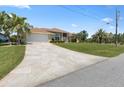 Large driveway leads to a beautiful home with well-maintained landscaping and mature palm trees at 9158 Melody Cir, Port Charlotte, FL 33981