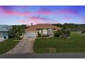 Sunset view of home with manicured lawn, mature palms, and a beautiful driveway at 9158 Melody Cir, Port Charlotte, FL 33981
