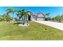 Well-manicured front yard with lush green grass and mature palm trees enhances the home's curb appeal at 9283 Newnan Cir, Port Charlotte, FL 33981