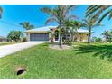 Charming home with a manicured lawn, mature palm trees, and an attached two-car garage at 9404 Arnaz Cir, Port Charlotte, FL 33981