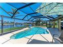 Screened in-ground pool and patio with view of canal, landscaping, and sunny blue sky at 9404 Arnaz Cir, Port Charlotte, FL 33981