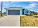 Exterior elevation of a light blue home featuring a two-car garage, front lawn and blue front door at 12359 Deepwoods Ave, Port Charlotte, FL 33981