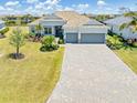 Beautiful home featuring a paver driveway, two car garage, and lush landscaping at 14556 Gaspar Loop, Port Charlotte, FL 33981