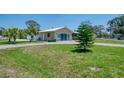 Single-story home featuring a metal roof, large front yard, mature landscaping, and a driveway at 1585 Poinciana Rd, Venice, FL 34293
