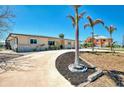 Charming home exterior featuring a circular driveway, palm trees, and a well-maintained lawn at 1915 Illinois Ave, Englewood, FL 34224