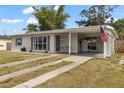 Inviting home with covered parking, a manicured lawn, and an American flag displayed out front at 21070 Gertrude Ave, Port Charlotte, FL 33952