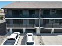 Condo building with screened balconies, two floors, and ground-level garages at 2769 N Beach Rd # 205, Englewood, FL 34223