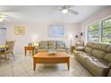 Spacious living room featuring tile floors, a ceiling fan, and large windows for natural light at 3189 Siesta Dr, Venice, FL 34293