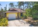 Bright yellow home with a driveway and garage, complemented by beautiful mature trees at 521 Artists Ave, Englewood, FL 34223