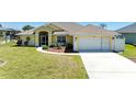 Inviting single-story home with a well-kept lawn, a two car garage, and manicured landscaping at 68 Long Meadow Ln, Rotonda West, FL 33947