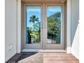 Inviting front double doors reflect lush greenery, offering a warm welcome to the home at 760 S Oxford Dr, Englewood, FL 34223
