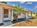 Inviting covered front porch with stone accents and a mature palm tree, enhancing curb appeal at 9149 Castlehill Ave, Englewood, FL 34224