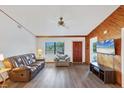 Bright living room with wood accent wall, ceiling fan, and laminate floors, open to other living spaces at 9149 Castlehill Ave, Englewood, FL 34224