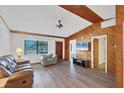 Cozy living room featuring wood-paneled walls, laminate flooring, and ample natural light at 9149 Castlehill Ave, Englewood, FL 34224