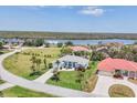 Aerial view of light blue home with lush front yard, palm trees, and a view of the nearby water at 11 Amberjack Ln, Placida, FL 33946