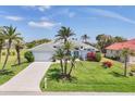 Charming single-Gathering home featuring a manicured lawn, mature palm trees, and a concrete driveway at 11 Amberjack Ln, Placida, FL 33946