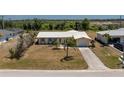 Inviting single-story home with a tidy front yard, concrete driveway and mature landscaping in the front at 113 Annapolis Ln, Rotonda West, FL 33947