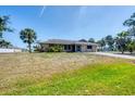Inviting single-story home with a lush front lawn, mature palm trees, and a welcoming facade at 11869 Newgate Ave, Port Charlotte, FL 33981