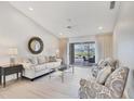 Bright living room featuring light wood floors and a sliding door view to the pool at 119 Fairway Rd, Rotonda West, FL 33947