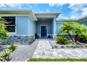Inviting entrance featuring a stone paver walkway leading to a charming blue front door at 13348 Boabadilla Ln, Port Charlotte, FL 33981