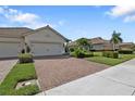 Wide brick driveway leading to the garages, framed by manicured lawns and landscaping at 1339 Backspin Dr, Englewood, FL 34223