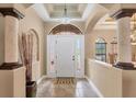 Bright foyer with a high decorative ceiling, tiled floor, columns, and a large front door at 15092 Chinook Way, Port Charlotte, FL 33981