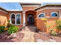 Inviting front entrance with an arched doorway, decorative windows, and lush landscaping at 15092 Chinook Way, Port Charlotte, FL 33981