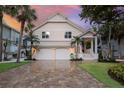 Inviting two-story home with a paved driveway, two-car garage, and manicured lawn with tropical landscaping at 16716 Grande Quay Dr, Boca Grande, FL 33921