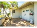 Charming front entrance featuring double doors, decorative shrubbery, and a welcoming ambiance with palm trees at 204 Bunker Rd, Rotonda West, FL 33947