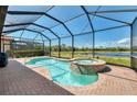 Screened-in pool and spa with a brick patio overlooks a serene pond at 23590 Copperleaf Dr, Venice, FL 34293
