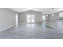Large living room with vaulted ceilings, gray wood-look tile flooring, and access to the kitchen and dining areas at 5273 Gillot Blvd, Port Charlotte, FL 33981