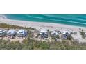 An aerial perspective capturing several beachfront homes, bordered by lush greenery and pristine ocean waters at 6890 Palm Island Dr, Placida, FL 33946