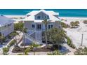 A stunning two-story beach house boasts detailed latticework, a pristine white staircase, and lush tropical landscaping at 6890 Palm Island Dr, Placida, FL 33946