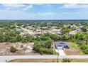 Aerial view of a charming blue single-Gathering home with an attached garage, lush landscaping, and a long driveway at 7332 Brandywine Dr, Englewood, FL 34224