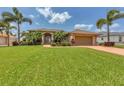 Inviting home with a green lawn, mature palm trees, and a spacious driveway leading to the attached garage at 8180 Burwell Cir, Port Charlotte, FL 33981