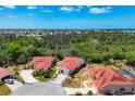 An aerial shot shows a home with a red tile roof, surrounded by mature trees and manicured lawns at 8320 Creekview Ln, Englewood, FL 34224