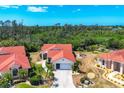This aerial view showcases the house with its distinctive red tile roof and lush tropical landscaping at 8320 Creekview Ln, Englewood, FL 34224