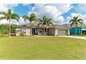 Beautiful single-story home featuring mature palm trees and a meticulously maintained lawn at 9211 Koma St, Port Charlotte, FL 33981