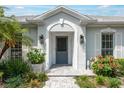 Inviting front entrance featuring a gray front door, decorative sconces, and lush landscaping at 1 Curacao Cir # 44, Englewood, FL 34223