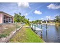 Backyard view with lush green grass, canal access, a small pier, and a fenced-in yard at 10064 Cocoa Beach St, Port Charlotte, FL 33981