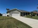 Single-story home features a two-car garage, landscaped front yard, and a concrete driveway at 174 Broadmoor Ln, Rotonda West, FL 33947