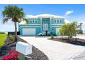 Stunning turquoise waterfront home with a white brick driveway, lush landscaping, and a two-car garage at 1900 Illinois Ave, Englewood, FL 34224