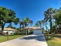 Inviting single-story home with a long driveway, lush green lawn, and mature trees at 237 Rotonda E Blvd, Rotonda West, FL 33947