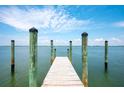 Picturesque view of a wooden dock extending into serene waters under a blue sky with fluffy clouds at 4065 N Beach Rd, Englewood, FL 34223