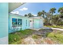 Exterior of a light blue home featuring lush palms, a front entrance, and attached garage on a sunny day at 4093 Pelican Shores Cir, Englewood, FL 34223